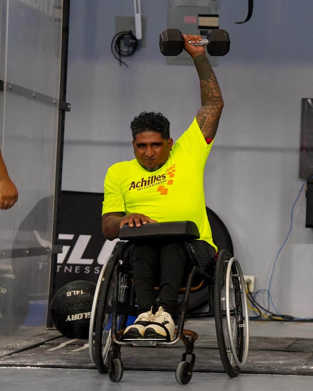 Un atleta hace press de mancuerna sentado en su silla de ruedas