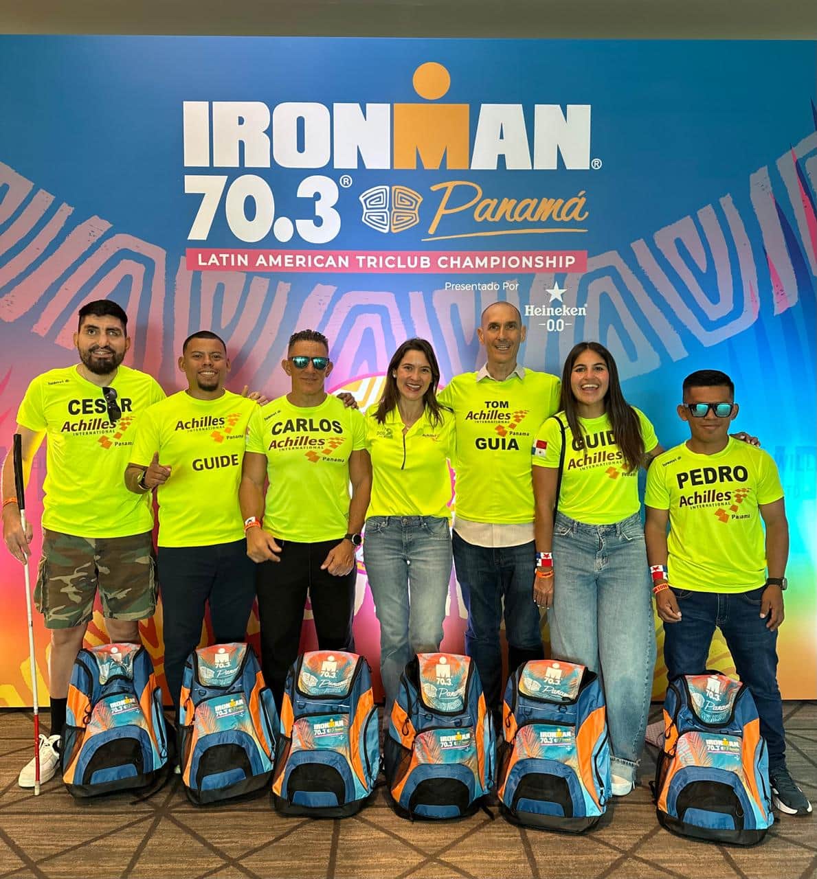 El equipo posa ante el fondo del Ironman 70.3 Panamá con sus mochilas de competencia