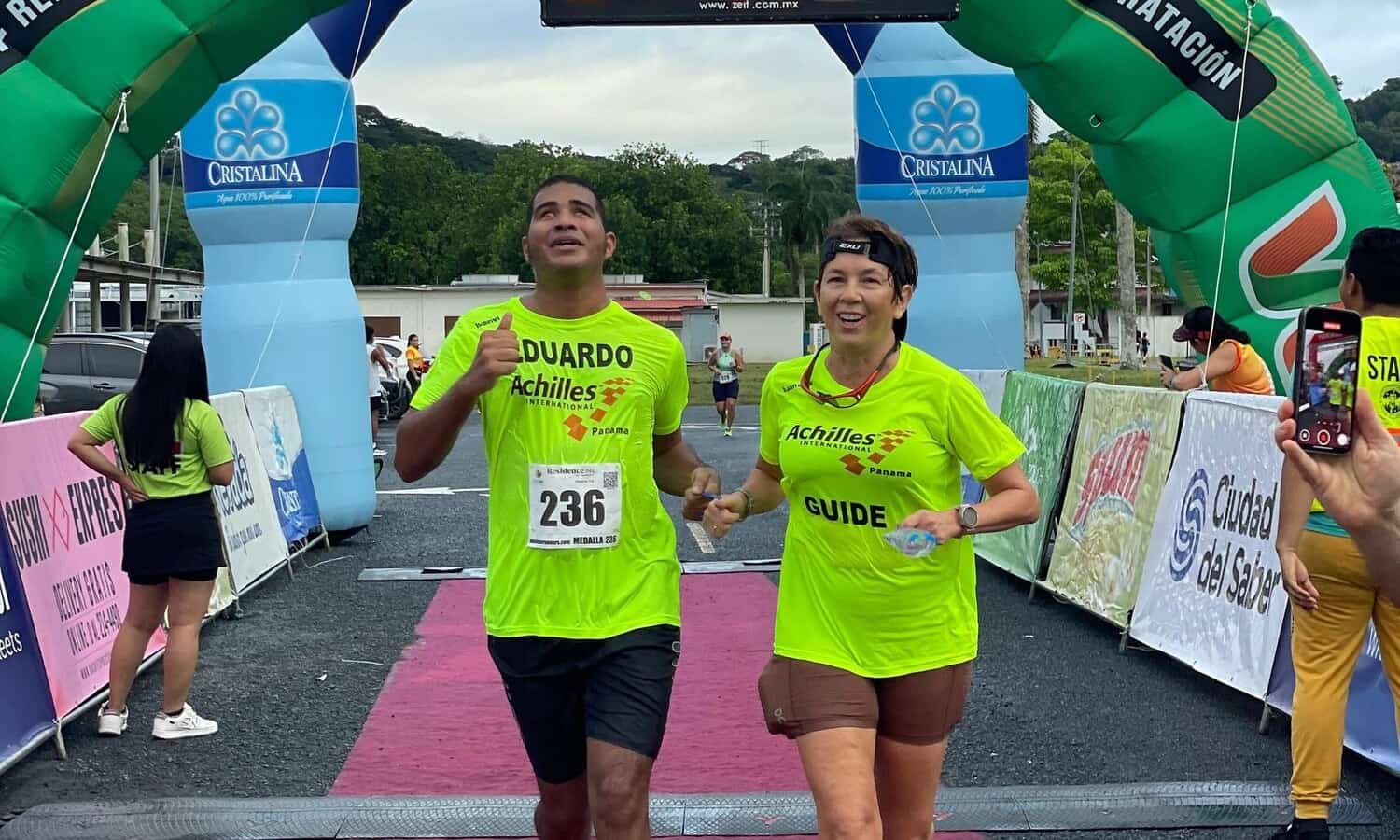 Un atleta y su guía cruzan juntos el arco de meta